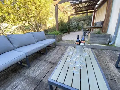 a patio with a couch and wine glasses on a table at Magnifique villa dans le massif de la Clape in Armissan