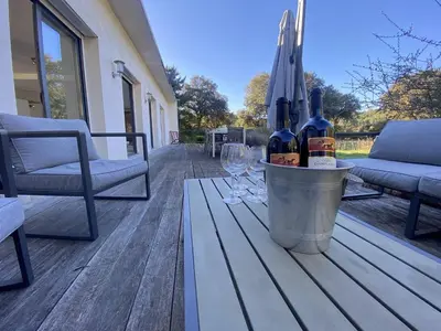 a bucket of wine bottles and wine glasses on a deck at Magnifique villa dans le massif de la Clape in Armissan