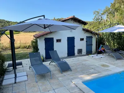 a patio with chairs and an umbrella next to a pool at l escapade Corbières in Lagrasse
