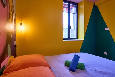 a bedroom with a bed with two blue towels on it at La Villa Orange - POP'ART - proche cité médiévale et centre ville à pied in Carcassonne