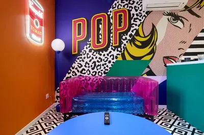 a room with a table with a pop sign in the background at La Villa Orange - POP'ART - proche cité médiévale et centre ville à pied in Carcassonne