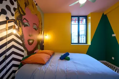 a bedroom with a bed with a painting on the wall at La Villa Orange - POP'ART - proche cité médiévale et centre ville à pied in Carcassonne