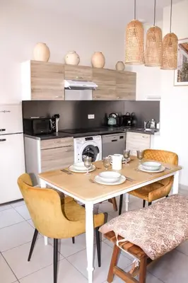 a kitchen with a wooden table with chairs and a microwave at Le Nayrac l Hypercentre l Parking privé in Castres