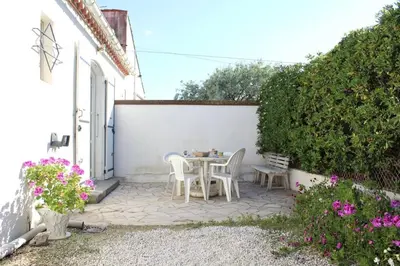 a patio with a table and chairs next to a white wall at Maison 3 pièces PORT LA NOUVELLE PN000-156 in Port-la-Nouvelle