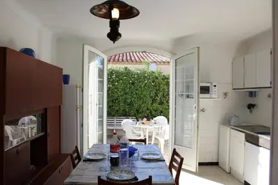 a kitchen with a table and a dining room with a table and chairs at Maison 3 pièces PORT LA NOUVELLE PN000-156 in Port-la-Nouvelle