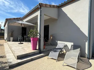 a patio with chairs and an umbrella next to a building at La Maison Laurier in Lézignan-Corbières