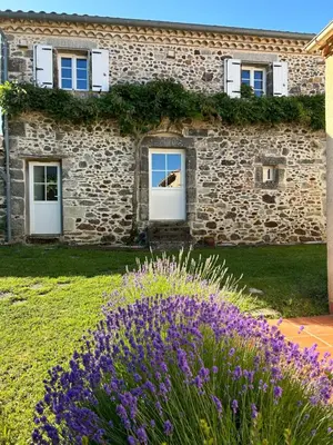 a stone building with purple flowers in front of it at Aux portes du Sidobre in Noailhac