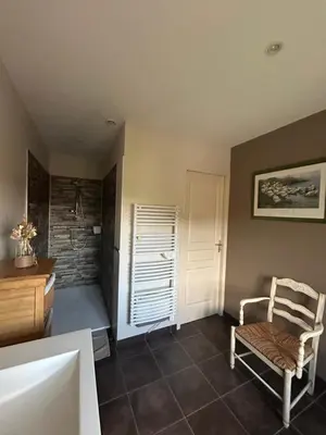 a bathroom with a sink and a chair in a room at Aux portes du Sidobre in Noailhac