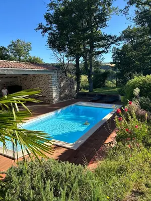 a swimming pool in a yard next to a house at Aux portes du Sidobre in Noailhac