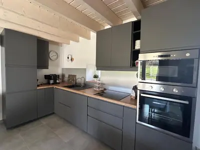 a kitchen with gray cabinets and a stove top oven at Aux portes du Sidobre in Noailhac