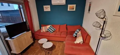 a living room with a red couch and a flat screen tv at Gruissan Maison familiale 2 à 6 personnes - 3 chambres et 2 SDB ! in Gruissan