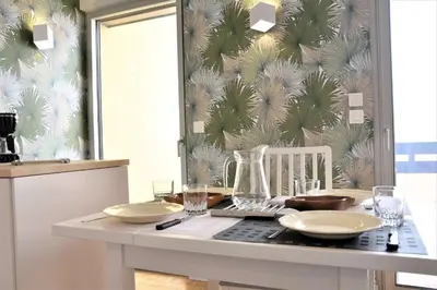 a kitchen with a table with plates and glasses at Appartement Rénové avec Balcon sur le Port GN460-010 in Gruissan