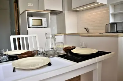 a kitchen with a table with plates and glasses on it at Appartement Rénové avec Balcon sur le Port GN460-010 in Gruissan