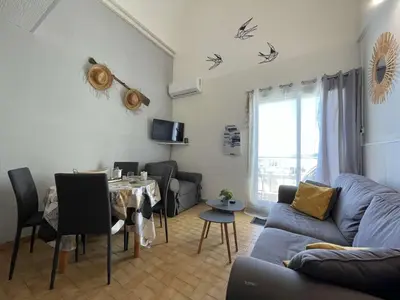 a living room with a table and a blue couch at Appartement climatisé résidence Grande Voile GN160-434 in Gruissan