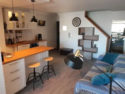 a living room with a couch and a kitchen at Vue sur les voiliers in Gruissan