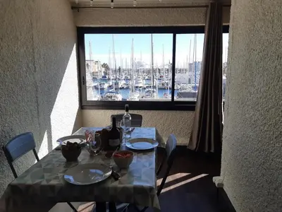 a table with a view of a harbor from a window at Vue sur les voiliers in Gruissan