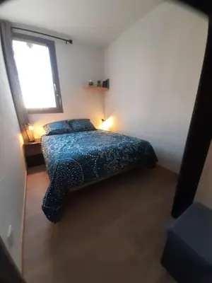 a bedroom with a bed with a blue comforter and a window at Vue sur les voiliers in Gruissan