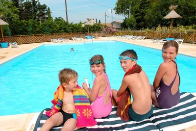 four children in bathing suits sitting next to a swimming pool at Azureva Sigean in Sigean
