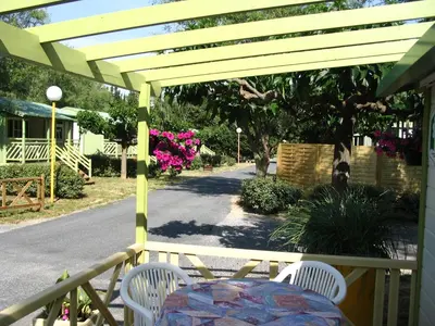 a table and chairs on a porch with a pergola at Azureva Sigean in Sigean