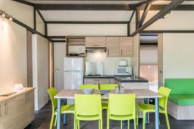 a kitchen and dining room with a table and yellow chairs at Azureva Sigean in Sigean