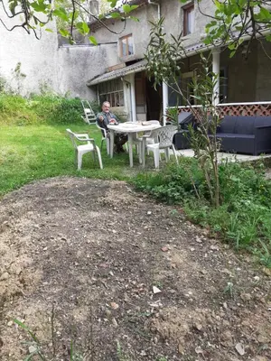 a man sitting at a table in a yard at Maison calme in Payrin-Augmontel