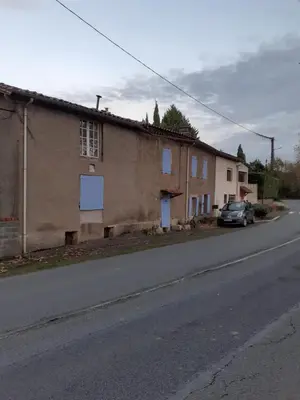 a building on a street with a car parked next to it at Maison calme in Payrin-Augmontel