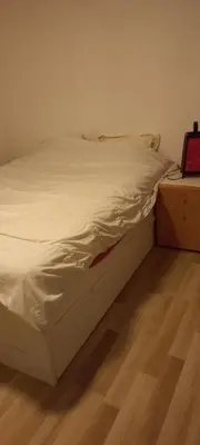 an unmade bed in a bedroom with a wooden floor at Maison calme in Payrin-Augmontel