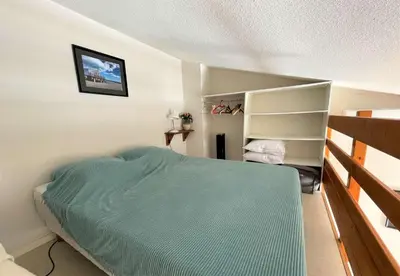 a bedroom with a green bed and a shelf at Pavillon climatisé - proche plage du grazel Gruissan GN510-019 in Gruissan