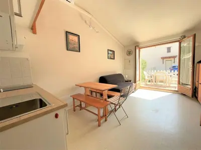 a living room with a table and a couch and a kitchen at Pavillon climatisé - proche plage du grazel Gruissan GN510-019 in Gruissan