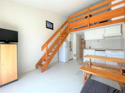 a living room with a loft bed and a kitchen at Pavillon climatisé - proche plage du grazel Gruissan GN510-019 in Gruissan
