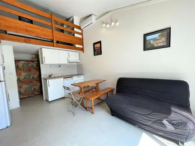 a bedroom with a bed and a table and a kitchen at Pavillon climatisé - proche plage du grazel Gruissan GN510-019 in Gruissan