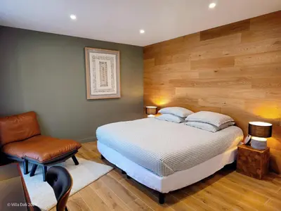 a bedroom with a bed and a chair at La Villa Dali in Lézignan-Corbières