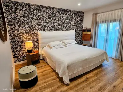 a bedroom with a white bed and a floral accent wall at La Villa Dali in Lézignan-Corbières