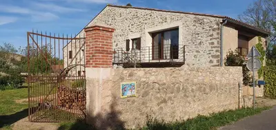 a building with a fence next to a stone wall at Château les Poules in Assignan
