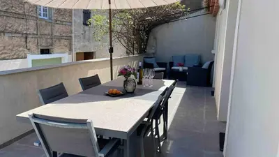 a table with chairs and an umbrella on a balcony at Modern apartment large terrace and beautiful view in Quarante