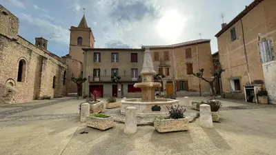 a fountain in the middle of a courtyard with a church at Modern apartment large terrace and beautiful view in Quarante
