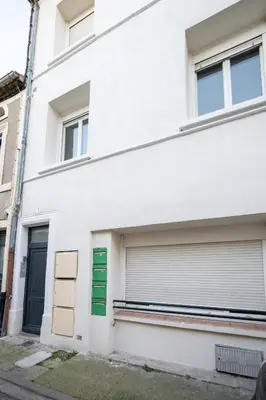 a white building with two garage doors at La Pause Carcassonnaise in Carcassonne