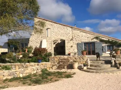 a stone building with a dog standing in front of it at Domaine Castelsec in Roquefort-des-Corbières