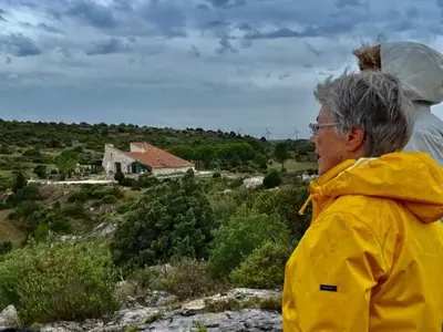 a woman standing on a hill looking at a house at Domaine Castelsec in Roquefort-des-Corbières