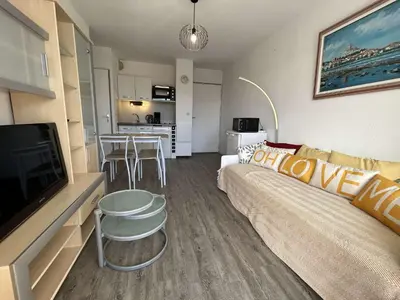 a living room with a couch and a tv and a kitchen at Appartement cosy proche plage & commerces GN450-A205 in Gruissan