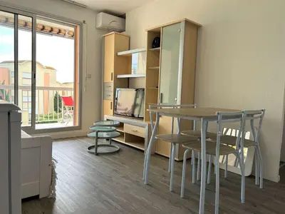 a dining room with a table and chairs and a tv at Appartement cosy proche plage & commerces GN450-A205 in Gruissan