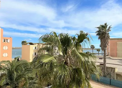 a group of palm trees in front of a building at Appartement cosy proche plage & commerces GN450-A205 in Gruissan