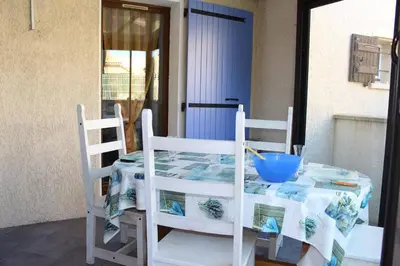 a table with two chairs and a blue bowl on it at Pavillon Cosy 3 pièces avec véranda et parking GN520-048 in Gruissan