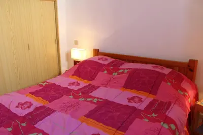 a bed with a pink quilt on it in a bedroom at Pavillon Cosy 3 pièces avec véranda et parking GN520-048 in Gruissan