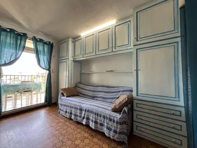a bedroom with a bed with cabinets and a window at Appartement Studio Cabine - Gruissan GN020-211 in Gruissan