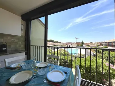 a dining table with a view of a balcony at Appartement Studio Cabine - Gruissan GN020-211 in Gruissan