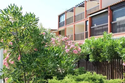 an apartment building with trees and pink flowers at Appartement Studio Cabine - Gruissan GN020-211 in Gruissan