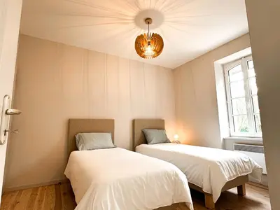 two beds in a room with a chandelier at Maison Agane - accès canal du midi, piscine chauffée in Pexiora