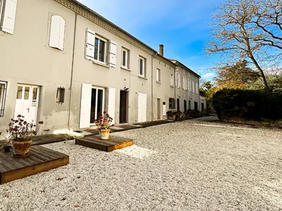 a building with two vases sitting on a gravel driveway at Maison Agane - accès canal du midi, piscine chauffée in Pexiora
