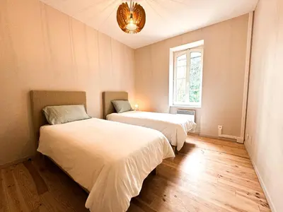 two beds in a room with a window and a chandelier at Maison Agane - accès canal du midi, piscine chauffée in Pexiora